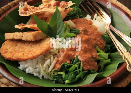 Nasi Pecel, die traditionellen javanischen Reisgericht aus gedämpftem Reis mit Gemüse Salat, Dressing, Tempeh, Tofu, und Cracker Stockfoto