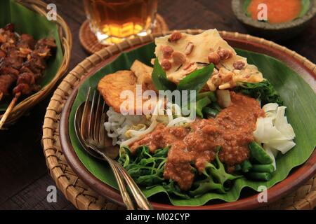 Nasi Pecel, die traditionellen javanischen Reisgericht aus gedämpftem Reis mit Gemüse Salat, Dressing, Tempeh, Tofu, und Cracker Stockfoto