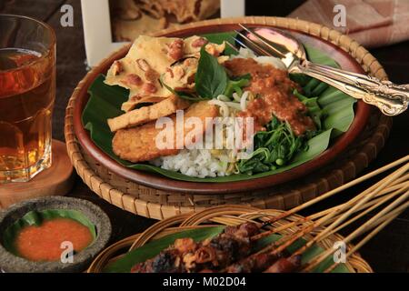 Nasi Pecel, die traditionellen javanischen Reisgericht aus gedämpftem Reis mit Gemüse Salat, Dressing, Tempeh, Tofu, und Cracker Stockfoto