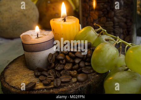 Kaffeebohnen auf rustikalen, mit Holz, zwei Kerzen und Trauben Stockfoto