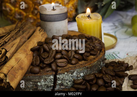 Eine gemütliche Szene von Kaffeebohnen auf rustikalen, mit Holz, eine Kerze und Stöcke von Zimt Stockfoto