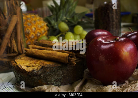 Gemütliche Szene von Kaffeebohnen auf rustikalen, mit Holz, Stöcke von Zimt, rote Äpfel, grüne Trauben Stockfoto