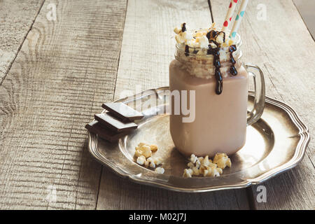 Schokolade Kaffee Milchshake mit Sahne im Glas Marmeladenglas auf grauem Hintergrund Holz serviert. Süßes Getränk. Stockfoto