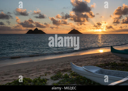 Sonnenaufgang über Mokulua Islands von Lanikai Beach mit Kanus in den Vordergrund Stockfoto