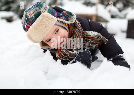 Im Hinblick auf ein glückliches Kind in warme Kleidung Spaß in einer verschneiten Garten. Junge Schnee genießen. Stockfoto