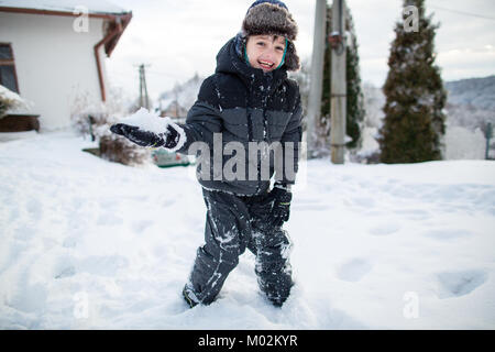 Lachendes Kind in warme Kleidung Spaß bei einer Schneeballschlacht. Junge Spaß im Schnee. Stockfoto