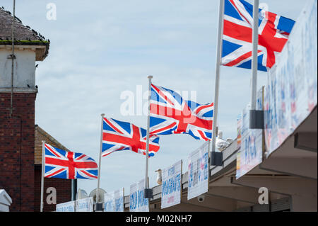 Union Jack Fahnen fliegen über Fast food Zeichen und vor blauem Himmel ein Sommertag am Meer in Littlehampton, West Sussex. Stockfoto