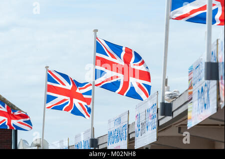 Union Jack Fahnen fliegen über Fast food Zeichen und vor blauem Himmel ein Sommertag am Meer in Littlehampton, West Sussex. Stockfoto