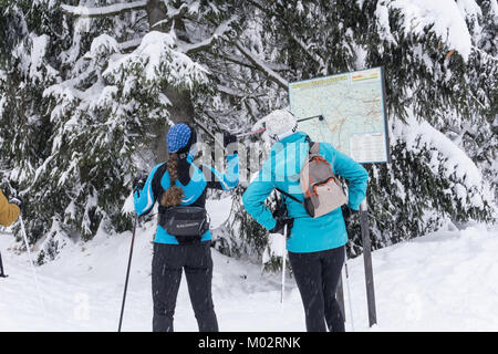 Zwei Frauen Skifahrer auf der Suche nach einem Cross-country Route auf der Karte an. Jakuszyce, Riesengebirge, Riesengebirge, Polen, Europa. Stockfoto