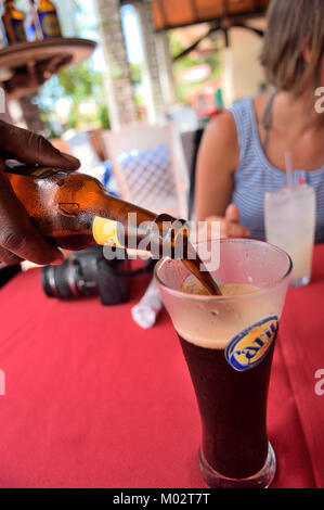 Kellner gießt ein Karibik Flasche Guinness, Grenada, Grenadinen, Karibik Stockfoto