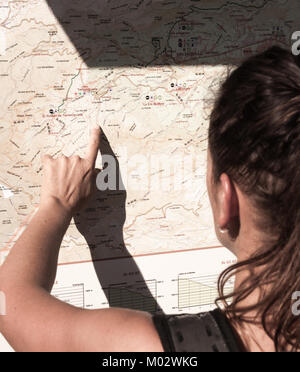 Weibliche Wanderer Karte lesen wandern Route Information Board auf Mountain Trail. Stockfoto