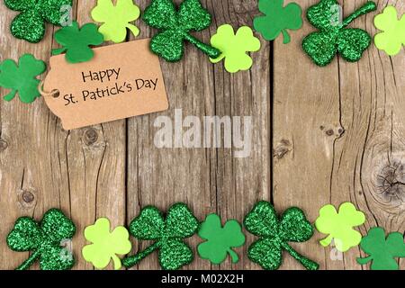 Happy St Patricks Day tag mit doppelter Grenze der glänzenden Shamrocks über eine rustikale Holz Hintergrund Stockfoto