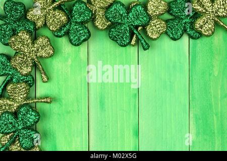 St Patricks Day Ecke Grenze der glänzenden glitter Shamrocks über ein grünes Holz Hintergrund Stockfoto