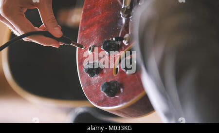 Musiker mit Stopfen und stimmt seine Gitarre, bevor eine Leistung, Hände, Nahaufnahme Stockfoto