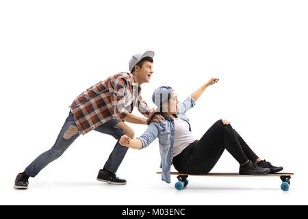 Teenager drücken ein junges Mädchen auf einem longboard auf weißem Hintergrund Stockfoto