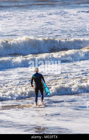 Surfer, Surfbrett Köpfe in das Meer Die große Wellen und abgehackt, Meer und Strand von Bournemouth Bournemouth Dorset UK im Januar zu machen Stockfoto