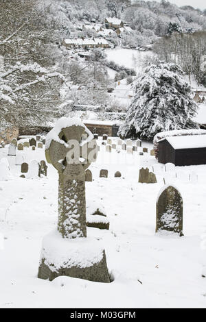 Grabsteine in St Andrew's Friedhof in Chedworth Dorf im Dezember Schnee. Chedworth, Cotswolds, Gloucestershire, England Stockfoto