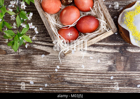 Blühende pflaume Zweig, Ostern Kuchen und bemalte Eier, Feder Zusammensetzung auf hölzernen Tisch von oben gesehen Stockfoto