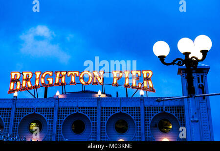 Brighton Pier hell rot und gelb neon Schild, Brighton Pier, ontop von Brighton Pier Eingang mit einer Straßenlaterne hinter, nachts genommen, blau Hu Stockfoto