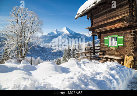 Schöne Aussicht von malerischen weißen Winter wonderland Bergkulisse in den Alpen mit traditionellen Holzmöbeln Mountain Chalet an einem kalten sonnigen Tag mit blauen Sk Stockfoto