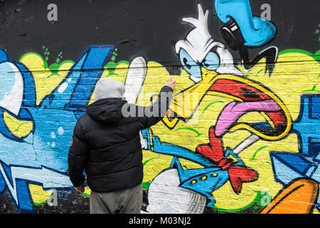 Brick Lane, East London ist eine kreative Zone für Künstler. Diese Bilder records Graffiti Künstler, beendet ein Stück Kunst. Stockfoto