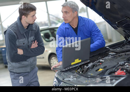 Schüler mit Lehrer, die Reparatur eines Autos während der Lehrzeit Stockfoto