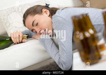 Betrunkene junge Frau schlafend auf dem Bett Stockfoto