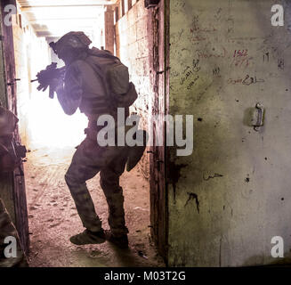 Eine erweiterte Operatoren Ausbildung Student einen Raum betritt und sucht nach Bedrohungen beim Üben voraus Professional zur Bekämpfung der Fähigkeiten der irakischen Streitkräfte bei der Terrorismusbekämpfung Service Academy, Bagdad, Irak, 23 Dezember, 2017 zu professionalisieren. Das CTS-Akademie trainiert irakische Armee Soldaten der Special Operations Forces, die später für SOF Einheiten ausgewählt werden kann und eine entscheidende Rolle für die Schaffung einer sichereren irakische Nation. CJTF-OIR ist die globale Koalition zu besiegen ISIS im Irak und in Syrien. (U.S. Armee Stockfoto