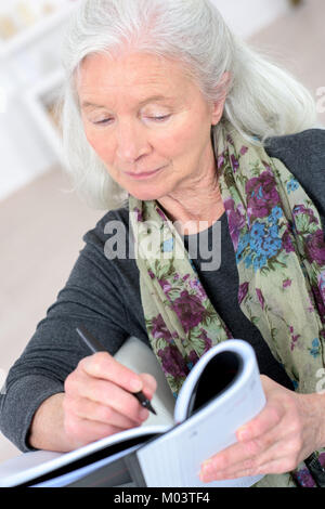 Ältere Frau Kreuzworträtsel tun Stockfoto