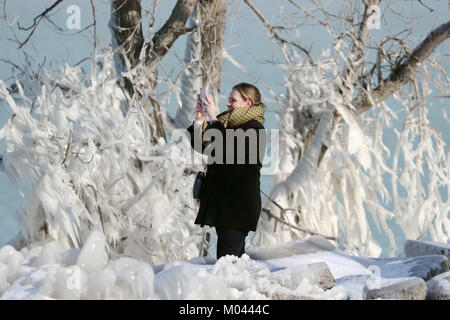 Chicago, USA. 18 Jan, 2018. Eine Frau nimmt Fotos von Eis bedeckt Bäume im nördlichsten Insel von Chicago, USA, am 18.01.2018. Extrem kaltes Wetter schlägt US-Midwest diese Woche mit Schnee und Schnee Dusche, und viele Bäume am Ufer des Michigan See in der Innenstadt von Chicago sind mit Eiszapfen abgedeckt. Credit: Wang Ping/Xinhua/Alamy leben Nachrichten Stockfoto