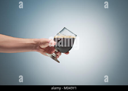 Nahaufnahme einer männlichen Hand hält ein Glas Bier Stockfoto