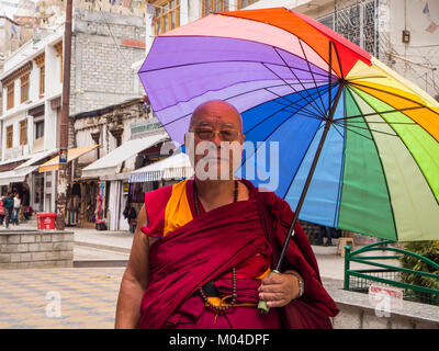 Ein buntes Bild von einem buddhistischen Mönch, der mit einem regenbogenfarbenen Regenschirm in der Hand Stockfoto
