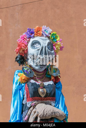 Bunte Tag der Toten Catrina Kostüm, mit einem übergroßen Kopf, Skelett Maske, und ein großer fake Blütenkopf Stück, in San Miguel de Allende, Mexiko Stockfoto