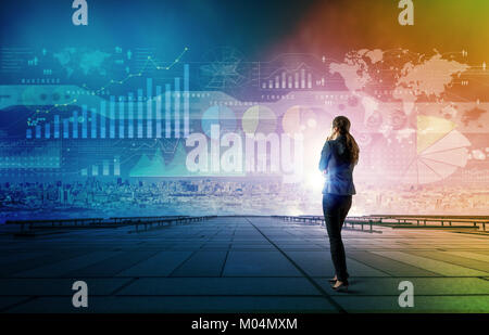 Stehende Frau, die verschiedenen Grafiken der Wirtschaft aussieht. Internet der Dinge. Informations- und Kommunikationstechnologie. Digitale Transformation. Abstrakte mixe Stockfoto