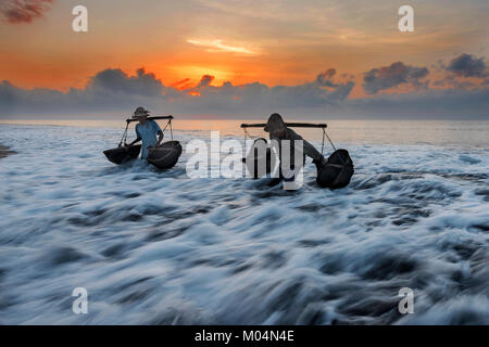 Indonesische Salz Landwirt von Kusamba Salz Bergbau Dorf auf Bali sammeln Meer Wasser in den Morgen für Salz produziert nach der traditionellen Methode Stockfoto