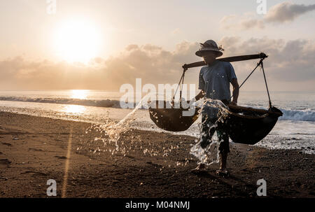 Indonesische Salz Landwirt von Kusamba Salz Bergbau Dorf auf Bali sammeln Meer Wasser in den Morgen für Salz produziert nach der traditionellen Methode Stockfoto