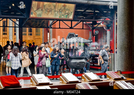 Menschen mit Räucherstäbchen vor einem Schrein in der beliebten Hsing Tian Kong oder Xingtian Tempel in Zhongshan District, Taipei, Taiwan zu beten. Stockfoto