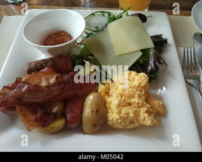 Ein Brunch-Teller mit verschiedenen Gerichten wie Eiern, Toast, Avocado, Speck und frischem Obst, wird in der Regel am späten Vormittag oder am frühen Nachmittag serviert. Stockfoto