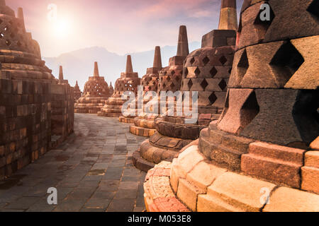 Erstaunlich sonnenaufgang Blick auf Stein Stupas am alten Borobudur Mahayana-buddhistischen Tempel gegen die strahlende Sonne für den Hintergrund. Große religiöse Architektur. Ma Stockfoto