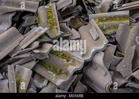 Diese Abbildung zeigt eine Nahaufnahme gebrochener schwarzer Dachziegel, möglicherweise durch Witterung oder Beschädigung. Dachziegel, insbesondere schwarze, werden in der Konstruktion wegen ihrer Haltbarkeit und ästhetischen Eigenschaften häufig verwendet. Das Bild zeigt den typischen Verschleiß von Dachmaterialien im Laufe der Zeit. Stockfoto