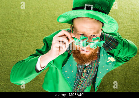 Hohe Betrachtungswinkel von bärtigen Mann in Grün Kostüm Klee geformte Brille und Kamera, st patricks day Konzept Stockfoto