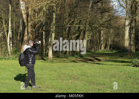 Professionelle männlichen Natur Fotograf Fotografieren auf kalten Wintermorgen. Aufnahmen im Freien, Canon Ausrüstung bereit: Kamera balanciert, Objektiv erweitert. Stockfoto