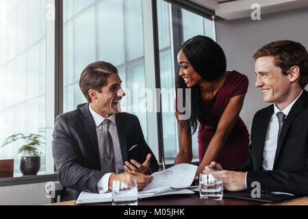 Corporate Business Professionals in einer Sitzung im Büro und Arbeiten an Dokumenten. Geschäftsleute, die Unterzeichnung eines Vertrags Papiere und lächelnd. Stockfoto