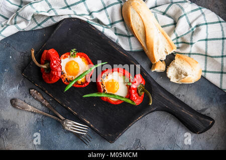 Gebackene rote Paprika gefüllt mit Eiern und Würstchen mit Brot und grüne Bohnen, Ansicht von oben. Stockfoto