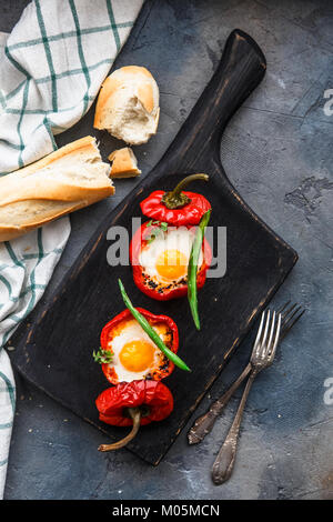 Gebackene rote Paprika gefüllt mit Eiern und Würstchen mit Brot und grüne Bohnen, Ansicht von oben. Stockfoto