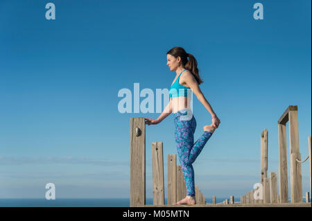 Frau, die ein Bein strecken auf einer Promenade am Meer. Stockfoto