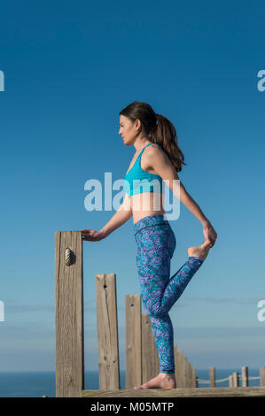 Frau, die ein Bein strecken auf einer Promenade am Meer. Stockfoto