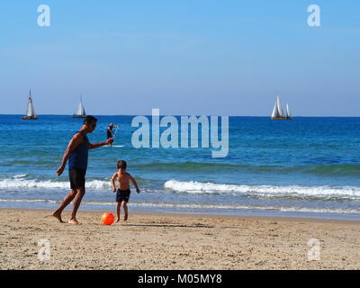 Vater und Sohn spielen Ball am Strand Stockfoto