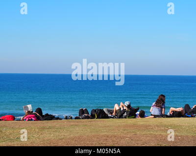 Eine Gruppe von Freunden in der Sonne liegen und relaxen Spaß an der Promenade in der Nähe der Strand vor dem Meer einen perfekten Tag mit strahlend blauem Himmel Stockfoto