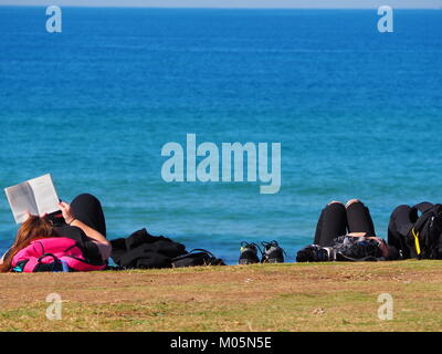 Eine Gruppe von Freunden in der Sonne liegen und relaxen Spaß an der Promenade in der Nähe der Strand vor dem Meer einen perfekten Tag mit strahlend blauem Himmel Stockfoto